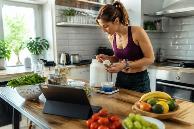 Femme calculant l'apport calorique journalier avec balance en cuisine équipée de fruits.